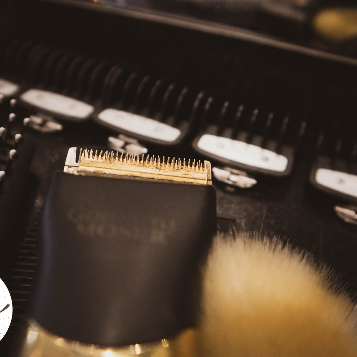 Máquina de corte e pincel de barbear pousados na bancada da Barbearia Lagartos